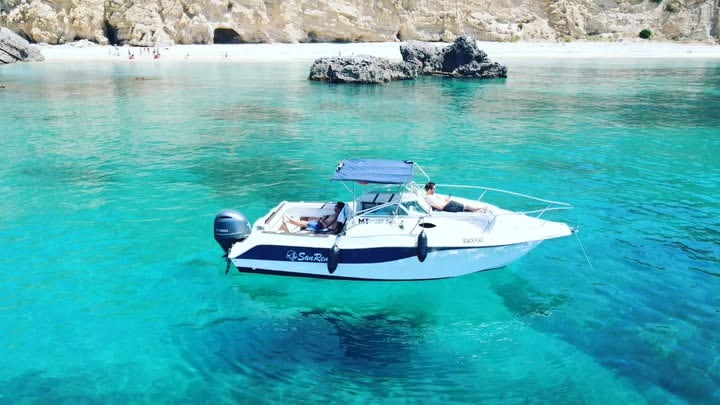 O barco Black Flag ancorado em águas turquesa, Sesimbra