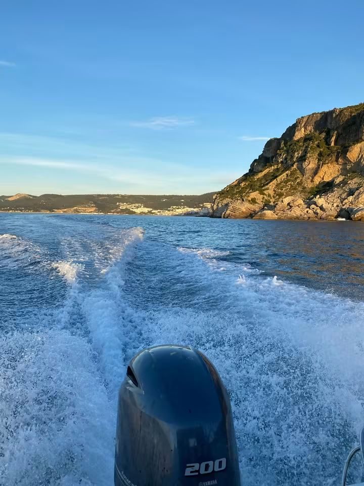 Esteira do barco ao pôr do sol junto às falésias de Sesimbra